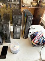 Three stacked home-video/audio components, CD spindle, smartphone, accessory bin on tabletop