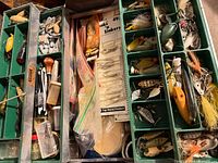 open tackle box showing trays of lures, hooks, sinkers, tools