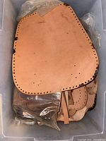 Stack of natural vegetable-tanned leather panels with pre-punched edges in bin