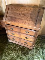 Front view of closed oak drop-front secretary with three drawers