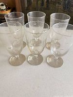 Front view of six clear etched stemmed glasses