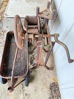 Overall view of rusted cast iron machine on stand with steel trough wagon