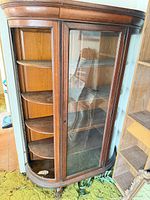 Front view of curved wood curio cabinet with glass door and shelves