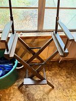 Full view of wooden director chair frame showing X-brace legs, armrests, and missing seat/back