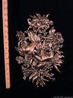 Front view of hammered copper floral plaque beside ruler showing approx 12 in height