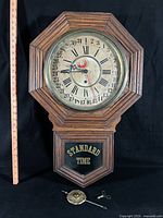 Front view of Gilbert drop regulator clock showing dial, glass, case and "STANDARD TIME" lower glass