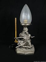 Full view of lamp showing figural base, shade, and scale