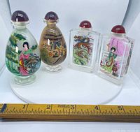All four snuff bottles front view showing shapes, stoppers and painted scenes