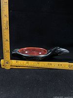 Side view of raven ashtray with rulers showing length ~6.5 in.