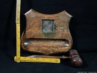 Front view of wooden inkwell stand showing square recess and pen groove with gavel beside, rulers for scale