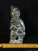 Front view of soapstone Inuit figure with fish next to ruler