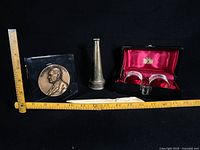 Group view with ruler reference showing bronze nozzle, Eastman medallion in acrylic, napkin rings in open case, plastic letter opener