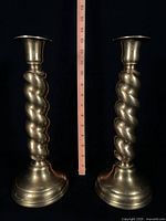 Front view of both brass barley twist candlesticks with ruler indicating height