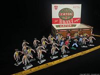 Group of plastic soldiers in front of Caton Havana cigar box with ruler for scale