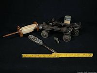 All items laid out: roller skates, key, kite string spool, carved paddle with ruler for scale