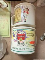Two Campbell’s advertising mugs stacked showing both graphics