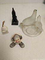 Group view of all four décor items—seal tealight holder, clown figurine, metal Empire State Building, wooden cat