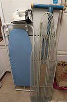 Overall view of iron atop blue-padded board beside mesh board