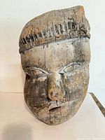 Front view of first wooden mask showing overall facial features and wear