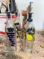 Three of the hand-painted glass bottles showing grape, pear and olive motifs with spouts attached