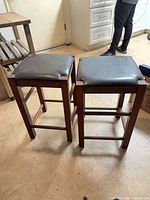 Two black leather wood stools side view