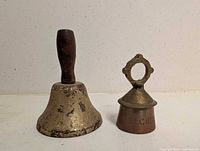Front view of both brass bells showing handles and patina