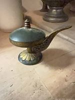 Side view of brass and enamel saccharin server showing handle and lid