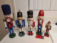Front view of six assorted wooden nutcrackers showing relative sizes and missing parts