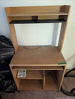 Front view of computer desk showing upper shelf, mid shelf, desktop and wheels