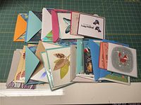Stack of assorted greeting cards and envelopes spread out on cutting mat