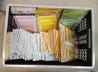 Plastic bin containing numerous sealed card kits organized by colour