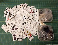 Pile of retail-carded buttons and two tubs of bagged buttons