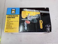 Front of box showing image and specifications of PowerFist 1320 lb electric cable hoist