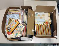Two open boxes showing numerous scrapbooking paper pads