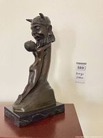 Assembled bronze sculpture front view showing male head with horns and female figure on marble base