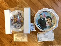 Both decorative plates in original packaging with certificates visible