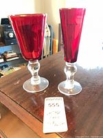 Both ruby red goblets on tabletop, clear view of stems and bowls
