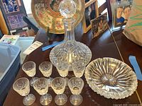 Overall view of decanter, eight cordial glasses and ashtray on table