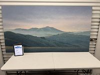 Full view of landscape painting on canvas resting on table