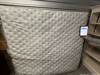 Full view of mattress standing upright, sealed in plastic