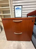Front view of brown two-drawer lateral file cabinet with handles and lock visible