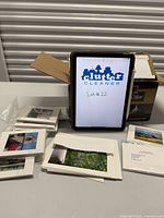 Stacks of wrapped art cards and envelopes on table beside open shipping box