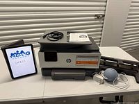 Printer, Echo Dot, hole punch, cords, paperwork on table