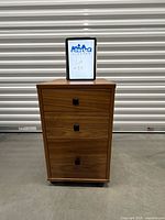 Full view of walnut 3-drawer cabinet on casters with black pulls