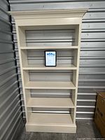 Full front view of cream bookcase showing five shelves and crown molding