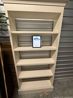 Front view of cream bookcase showing five shelves and crown molding