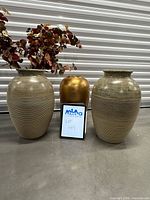 Front view of two taupe ribbed vases, gold vase between, faux stems displayed