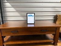 Full front view of coffee table showing drawer, shelf, and finish