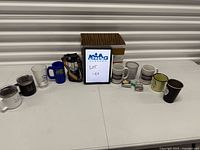 All items laid out on table including mugs, headlamp and small tools