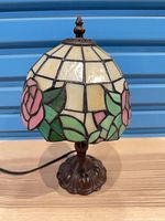 Full view of lamp showing stained glass rose shade and metal base